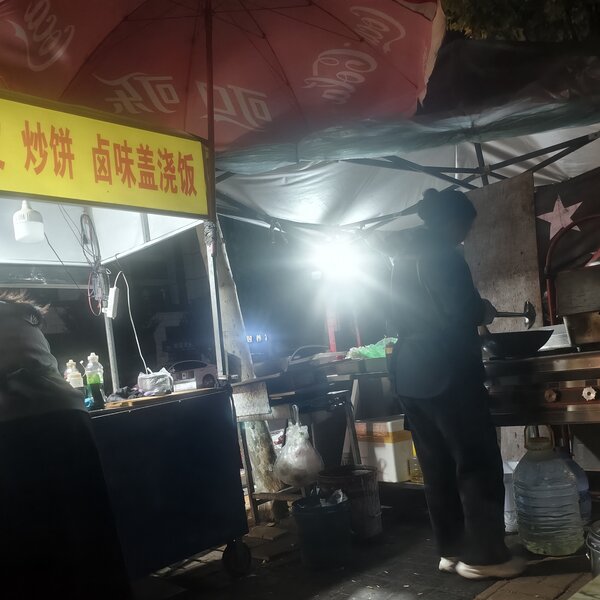摊位前的两个人，灯亮着，锅还热